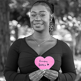 Woman holding a Project Pink heart showing her grandmother’s name, who faced breast cancer