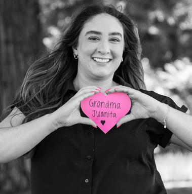 Woman holding a Project Pink heart with her grandmother’s name in honor of breast cancer awareness